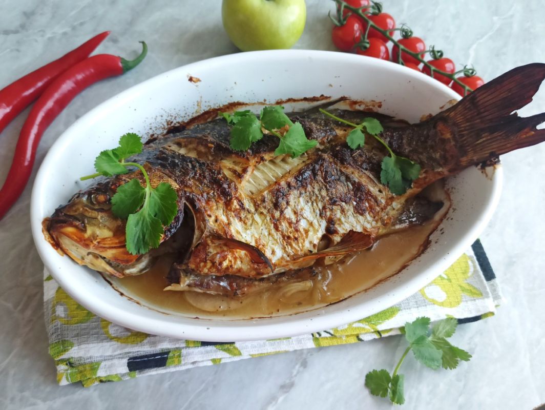 Карась, запечённый с луком и яблоком: простой рецепт для ценителей речной рыбы